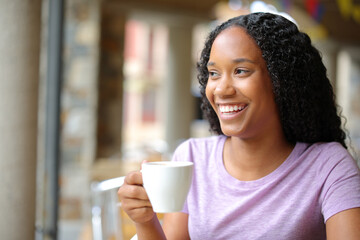 Happy black woman holding coffee cup and looking at side