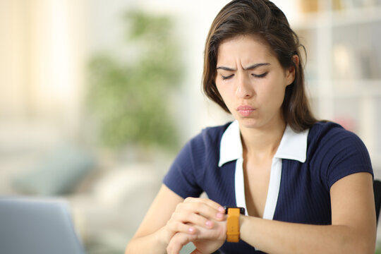 Worried woman checking smartwatch at home