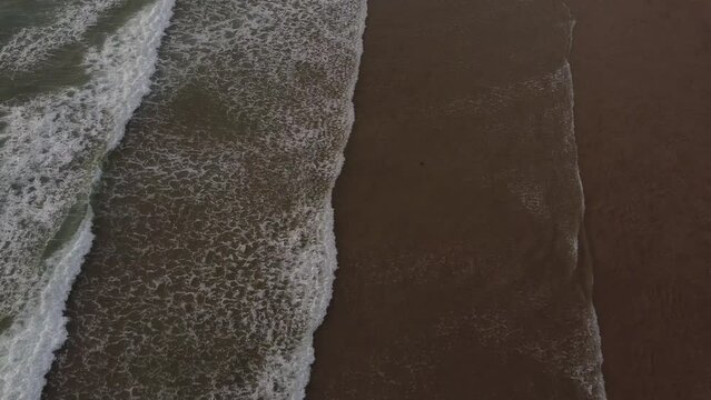 Aerial view of relaxing ocean waves crashing onto the shore