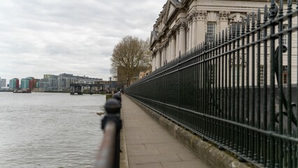 Fence of the University of Greenwich alongside the river in London under the cloudy sky