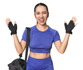Athletic Caucasian young woman with gym bag on studio background receiving a pleasant surprise, excited and raising hands.