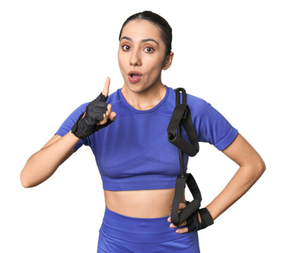 Athletic young Caucasian woman with resistance band on studio background having an idea, inspiration concept.