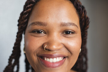 Young biracial woman with braided hair is smiling at camera in a modern business office