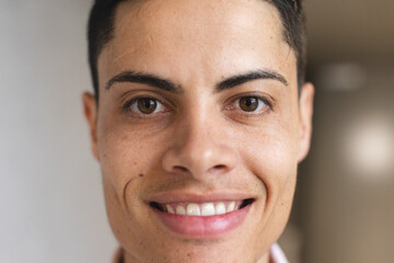 A young biracial man with short hair is smiling in a modern business office - Powered by Adobe