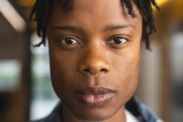 African American man with short dreadlocks looking at camera in a modern business office