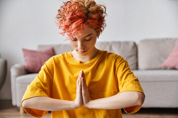 appealing extravagant queer person with red hair in vibrant yellow t shirt meditating at home