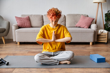 appealing extravagant queer person with red hair in vibrant yellow t shirt meditating at home