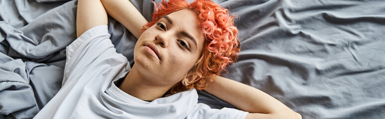 appealing extravagant person with red hair lying in her bed and looking away, leisure time, banner