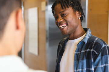 African American man talking to biracial man, both looking happy in a modern business office