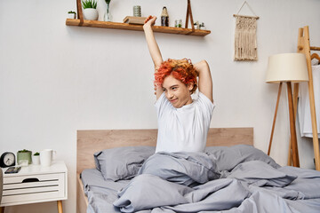 extravagant pretty queer person in casual attire waking up and stretching in her bed, leisure time
