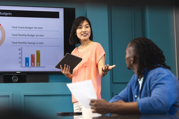 Asian woman presenting, African American man listening in a modern business office
