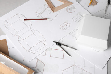 Creating packaging design. Drawings, boxes and stationery on light wooden table, above view