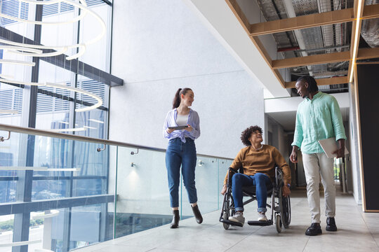 Diverse group of friends walking and talking in modern hallway in a modern business office