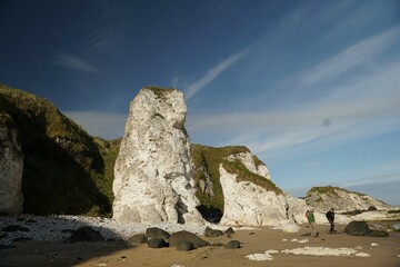 Scenic view of a coastline with huge rocks and cliffs covered with grass under the blue sky