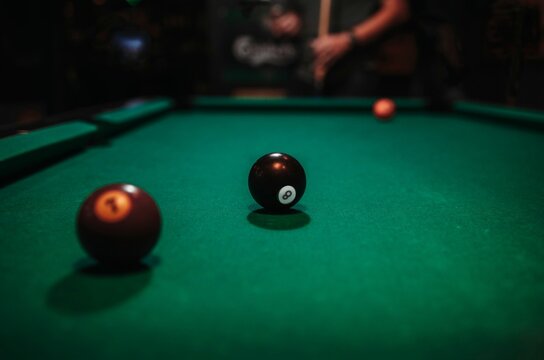 Close-up shot of balls on a pool table with a person in background