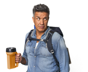 Hispanic trekker with backpack and flashlight dreaming of achieving goals and purposes