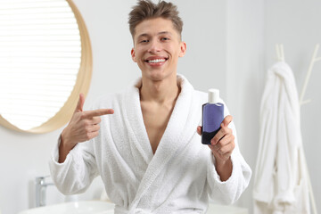 Young man pointing at mouthwash in bathroom