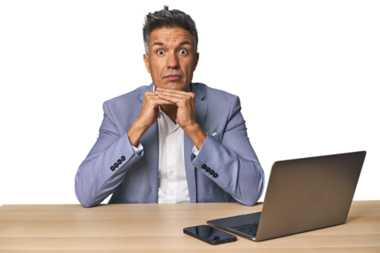 Elegant businessman at desk with laptop praying for luck, amazed and opening mouth looking to front. - Powered by Adobe