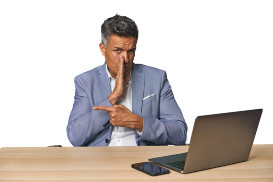 Elegant businessman at desk with laptop saying a gossip, pointing to side reporting something.