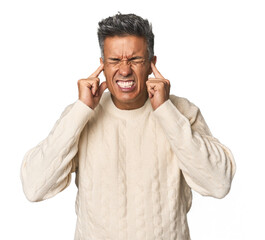 Middle-aged Latino man covering ears with hands.