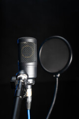 Close-up of a professional condenser studio microphone on a black background in a music studio. Vertical photo