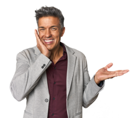 Middle-aged Latino man holds copy space on a palm, keep hand over cheek. Amazed and delighted.