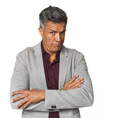 Middle-aged Latino man frowning face in displeasure, keeps arms folded.