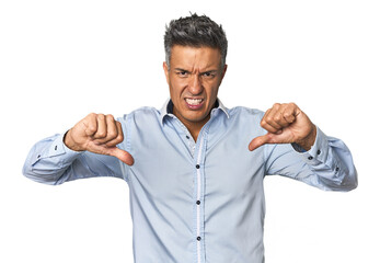 Middle-aged Latino man showing thumb down and expressing dislike.