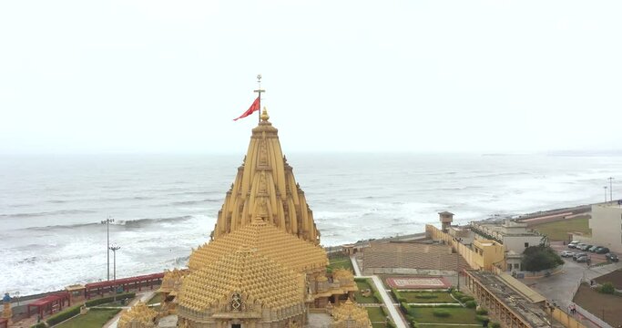 Aerial view of the Somnath temple with a waving flag in India by the sea