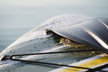 Close up of a Stand Up Paddle surf board or SUP on the lake with water drops. Gray background.