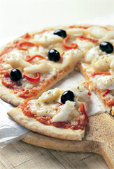 sliced cod and tomato pizza on wood