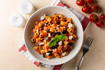 Flat lay of a plate with summer short pasta with eggplant, tomato and ricotta cheese, decorated...
