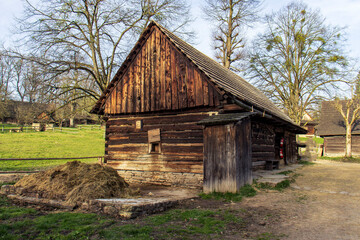 Old wooden barn in a historic wooden town. Trees and green grass. Nature around the wooden barn.