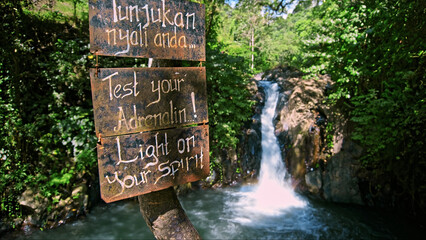 waterfall with rocks among tropical jungle with water falling down into river with the text on the billboard 