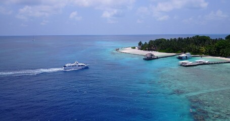 Obraz premium Aerial view of boats near a small island with trees in Maldives