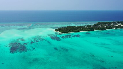 Obraz premium Aerial view of an island with houses and trees surrounded by the ocean