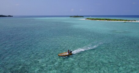 Aerial drone shot of a boat taking a tour around an island in the Maldives