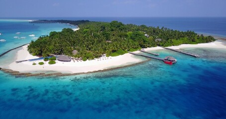 Aerial drone shot of a paradise island in the Maldives washed by the Indian Ocean