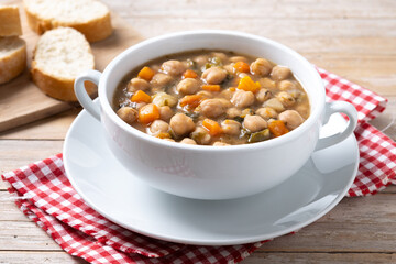 Chickpeas soup with vegetables in bowl on wooden table