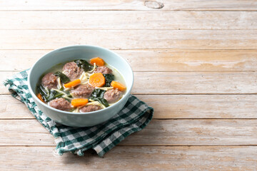 Italian Wedding Soup with meatballs and spinach on wooden table. Copy space