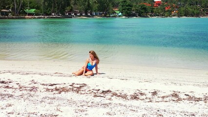 Obraz premium Sexy caucasian female sitting on a sandy coastline in Koh Phangan, Thailand