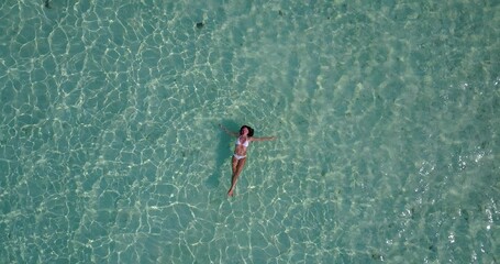 Overhead shot of a woman wearing a white bikini in the clear seawater