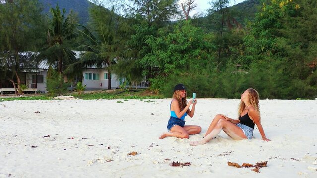 Smiling caucasian female taking pictures of her friend on a beach in Koh Phangan, Thailand