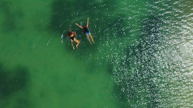 Overhead shot of two women swimming in the clear seawater in Koh Phangan, Thailand