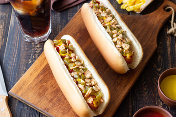 Hot dogs with grilled sausages, ketchup, mustard, fried onions and cucumbers. Fast food.