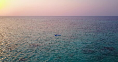 Fototapeta premium Beautiful view of a boat in a sea under the clear sky during sunset in Asia