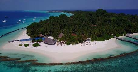 Aerial view of a resort on an island with turquoise water, a white sandy beach and tropical trees