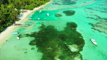Aerial shot of coral reefs under tranquil water and boats in the sea
