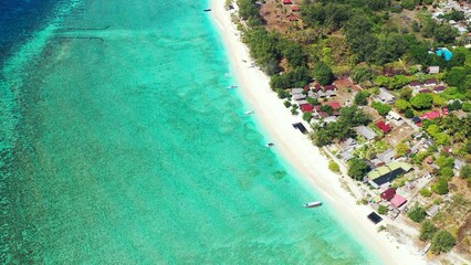 Aerial shot of a paradise island with tropical trees and villas surrounded by turquoise water