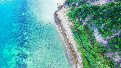 Aerial shot of ocean water covering the tropical island's coastline